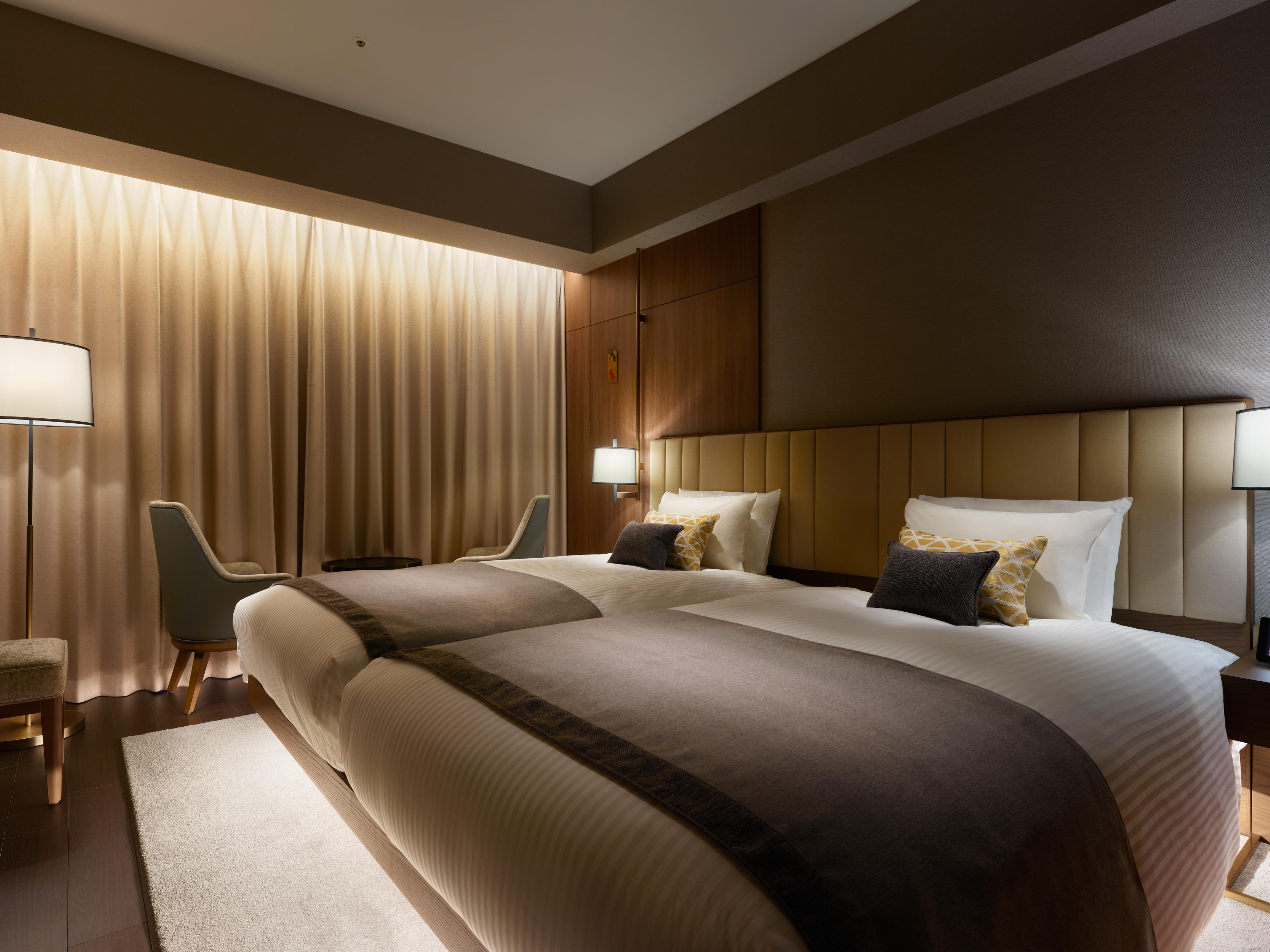 Mitsui Garden Hotel Roppongi Tokyo Premier Eksteriør bilde The photo shows a modern hotel room featuring two twin beds with elegant bedding. The room is adorned with soft, neutral tones and has a warm ambiance created by subtle lighting. A pair of bedside lamps provide additional light, and there is a cozy c